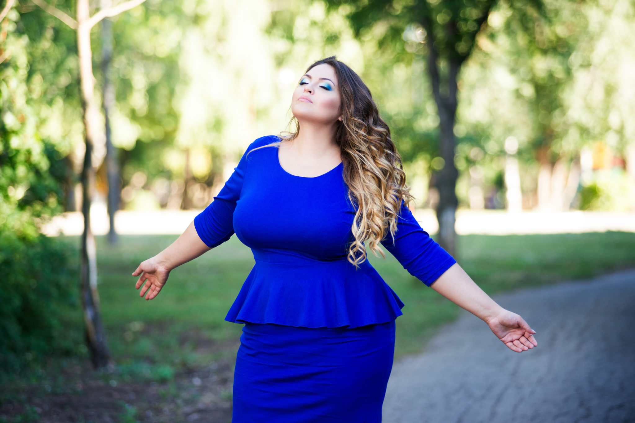 femme ronde en robe bleue éclatante dans un jardin